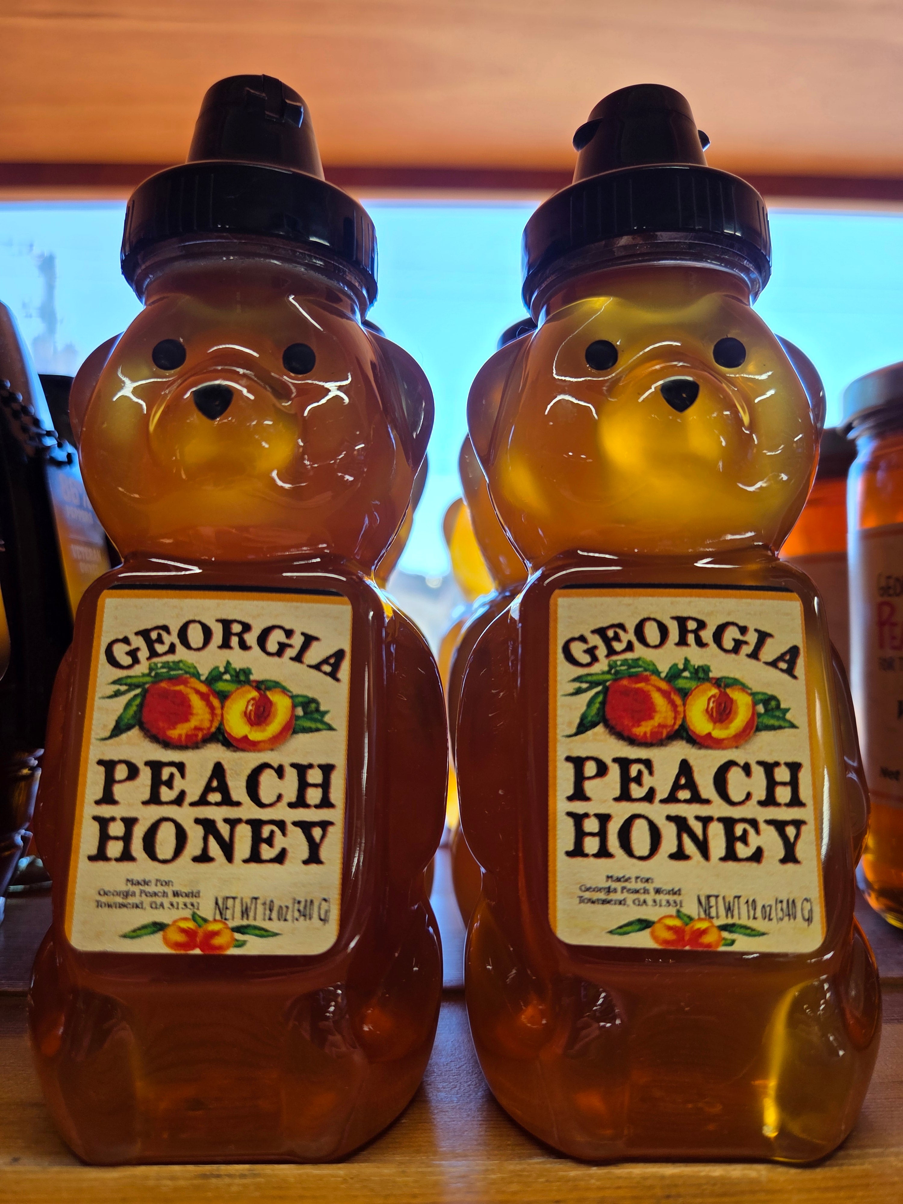 Two bottles of Georgia Peach Honey on a wooden surface.