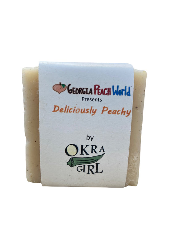 hand cut peach soap bar wrapped in thick strip of paper printed with Okra Girl's branding