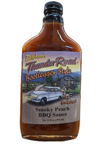 12 oz bootlegger style glass bottle with a shrink wrapped lid containing smoky peach BBQ sauce