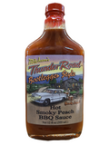 12 oz glass bootlegger style bottle with a shrink wrapped lid containing hot smoky peach bbq sauce