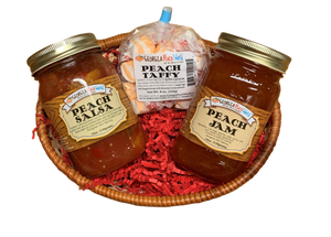 Small oval shaped basket with crinkled paper "grass". Basket is holding a standard glass mason jar containing peach jam, a standard glass mason jar containing peach salsa, and plastic packaged orange and white taffy wrapped in wax paper