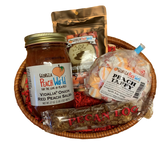 Small oval shaped wicker basket with crinkle paper, a Standard glass Mason Jar containing peach salsa, brown 2 oz foil pack containing pecan flavored coffee, plastic wrapped orange and white colored candy taffy wrapped in wax paper, and a plastic wrapped candy pecan log