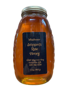 Tall thin and wide traditional queenline shape with ribbed edges glass jar containing raw wildflower honey