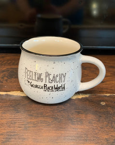 Small white 15 oz ceramic mug with black speckles. Text reads "Feeling Peachy" with Georgia Peach World branding underneath